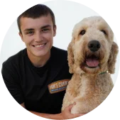 A young man smiling next to a large, curly-haired dog.